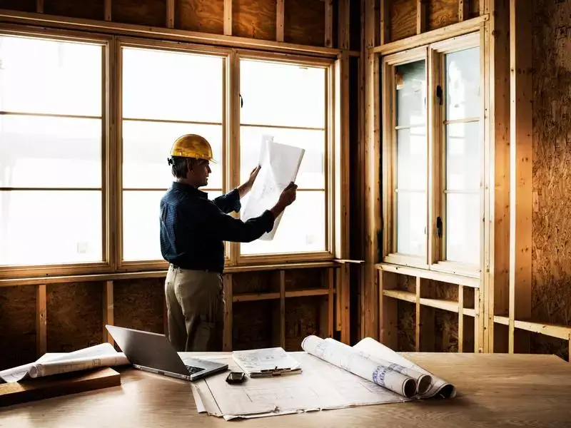 Builders Central Otago Contact Us - Architect reviewing blueprints indoors